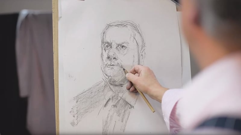 A man puts the finishing touches to a pencil portrait drawing