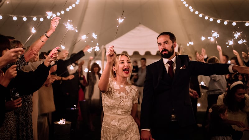 Newly married couple holding sparklers at their evening wedding reception in West Dean Gardens