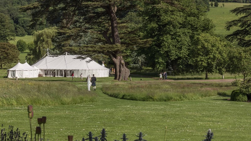 Bride and groom walking to marquee in West Dean Gardens