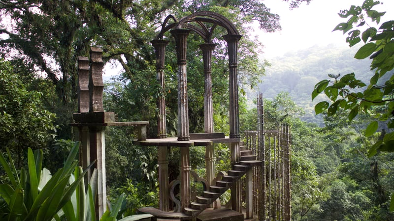 A view of large concrete pillars and structures reaching high into the tree tops of the Mexican jungle
