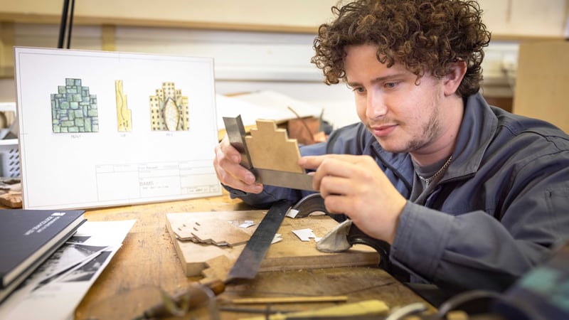 Finn Banwell at his workbench in the metals workshop, with his design in the background. Image credit: Chris Ison