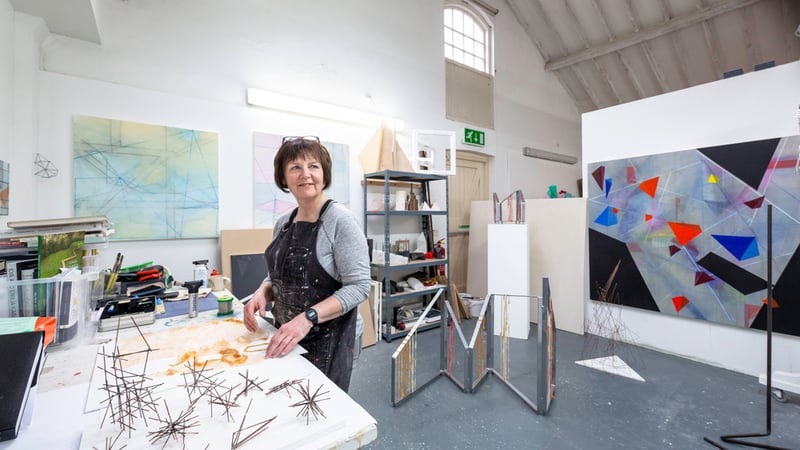 A student in the Fine Art Studio workspace, the large space features a workbench and the walls are filled with large-scale paintings and wire sculpture pieces