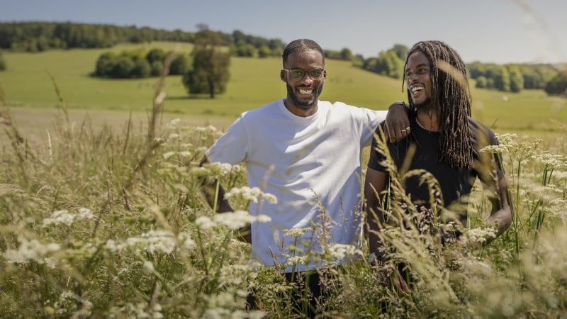 Resolve Collective artists Seth and Akil stand waist height in cow parsley with the parkland behind them