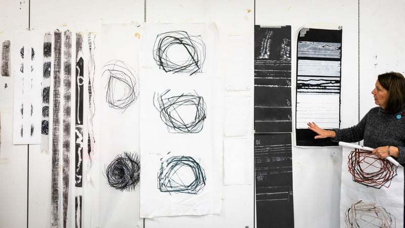 Student talking about her large scale line drawings displayed on a wall. Photo by Chris Ison