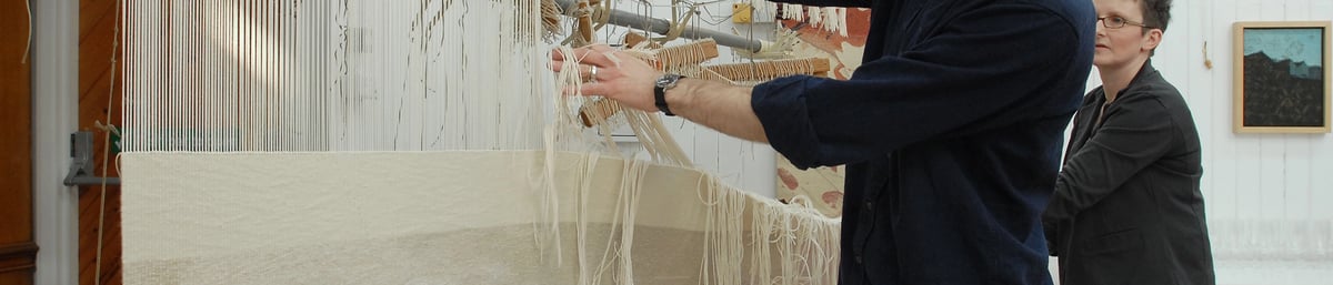 Philip Sanderson cutting off the black cat tapestry at West Dean Tapestry Studio