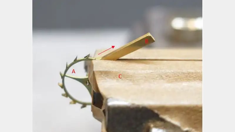 Figure 5: Escape wheel (A) and brass support (B) held together in a vice (C) 